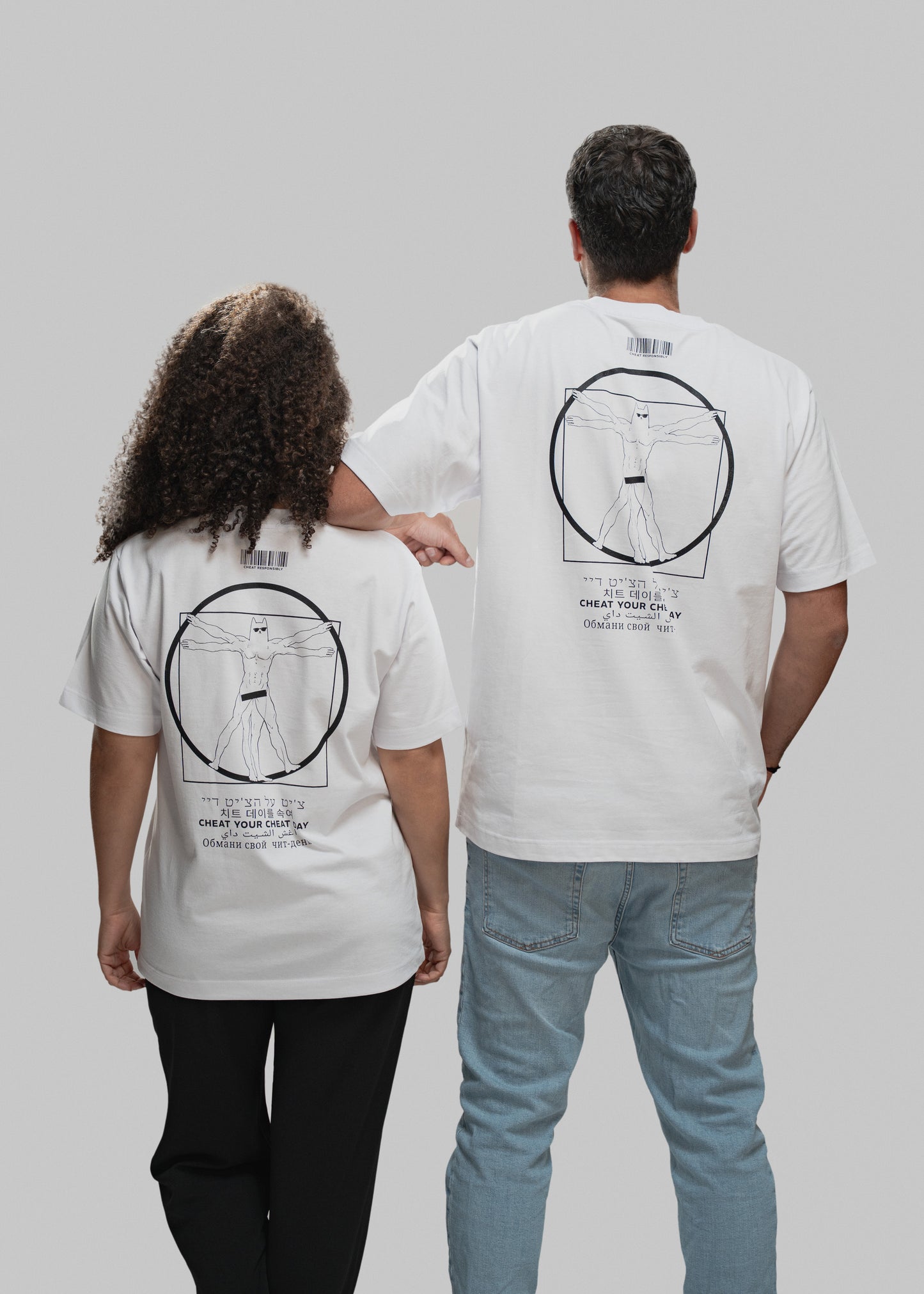 Das Bild zeigt zwei Personen von hinten vor grauem Hintergrund. Beide tragen weiße T-Shirts mit einem schwarzen, zentral platzierten Druck auf dem Rücken. Dieser zeigt eine an Leonardo da Vincis „Vitruvianischem Menschen“ angelehnte Figur mit Maske und Sixpack in einem Kreis und Quadrat. Unterhalb des Motivs steht der Claim „CHEAT YOUR CHEAT DAY“ in sechs verschiedenen Sprachen. Über dem Motiv befindet sich ein minimalistischer Barcode. Die linke Person trägt schwarze Hose und hat mittellanges, lockiges Haa
