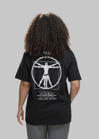 Eine Person mit lockigem Haar steht mit dem Rücken zur Kamera und trägt ein schwarzes T-Shirt. Auf dem Rücken ist ein auffälliges weißes Motiv zu sehen: Eine muskulöse Comicfigur mit Maske – stark an den „Vitruvianischen Menschen“ von Leonardo da Vinci angelehnt – steht mit ausgestreckten Armen und Beinen in einem Kreis und Quadrat. Der Charakter trägt nur eine enge Shorts. Oberhalb des Motivs befindet sich ein stilisierter Barcode mit der Aufschrift „CHEAT RESPONSIBLY“. Darunter steht der Satz „CHEAT YOUR 